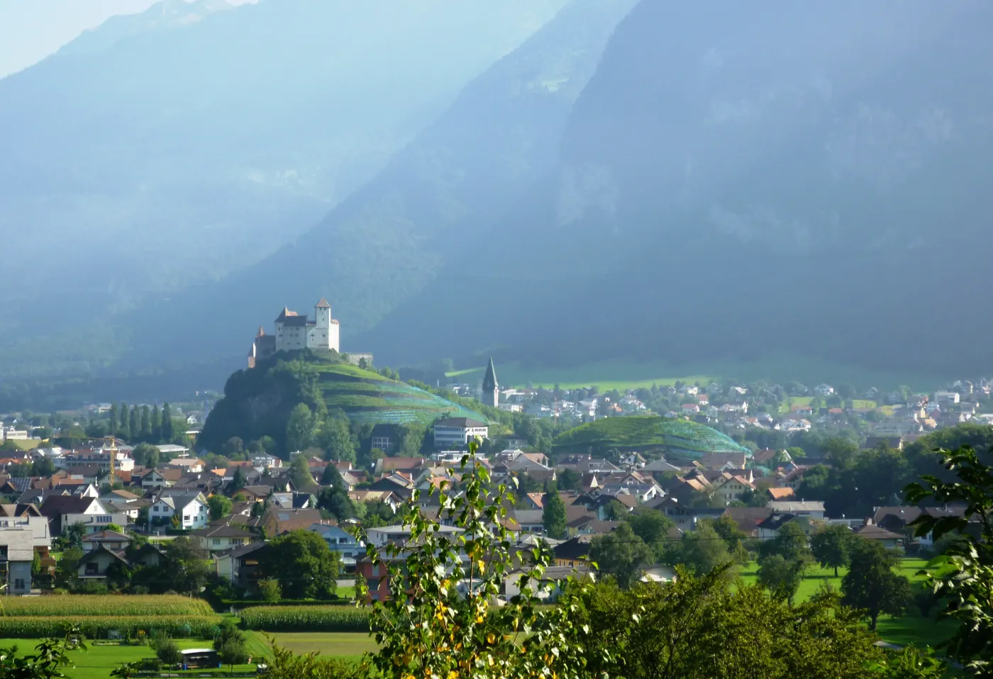 Gutenberg Castle on its hill above Balzers, the mountainsides behind it in haze